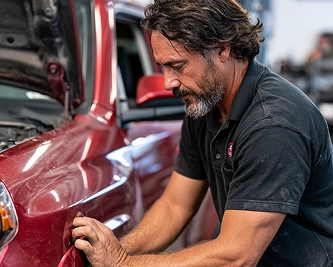 Technician inspecting a red vehicle
